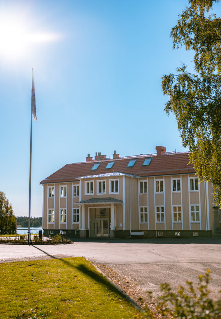 Ett stort gult hus bredvid en flaggstång